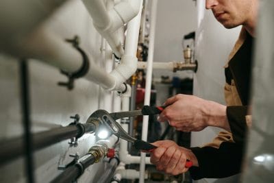 Technician inspecting commercial plumbing pipes in Torrance